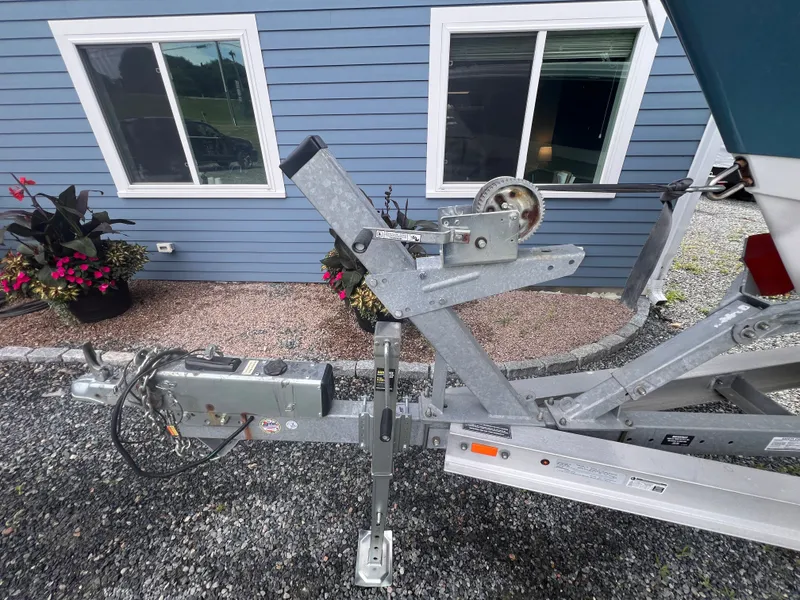 Slide: The Image of A boat trailer with a winch is parked on a gravel path in front of a blue building. - 39