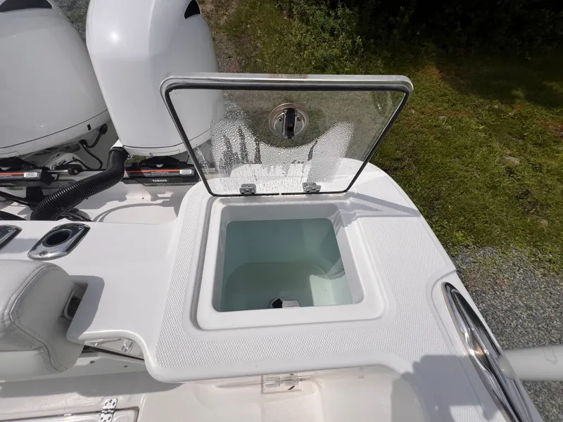 Slide: The Image of An open storage compartment on a 2021 Edgewater 262CC boat. It is located next to an engine. - 18