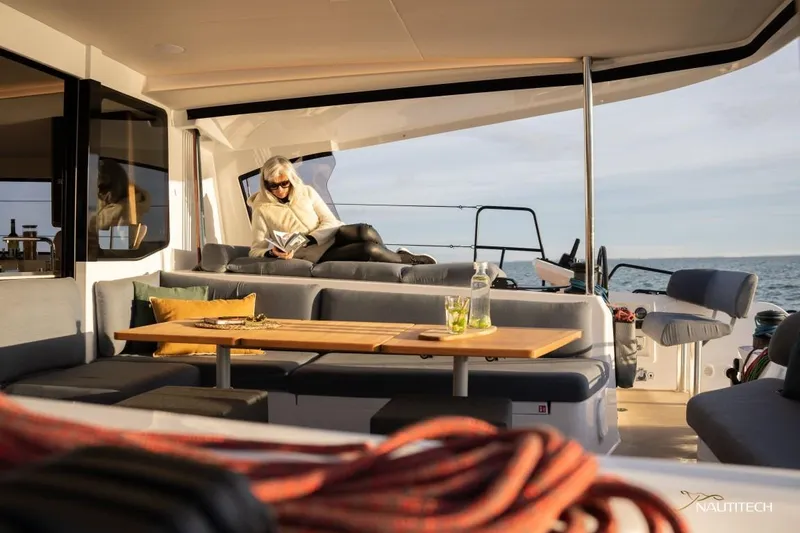 Slide: The Image of A woman reads on a luxurious catamaran with stylish seating and a table. - 17
