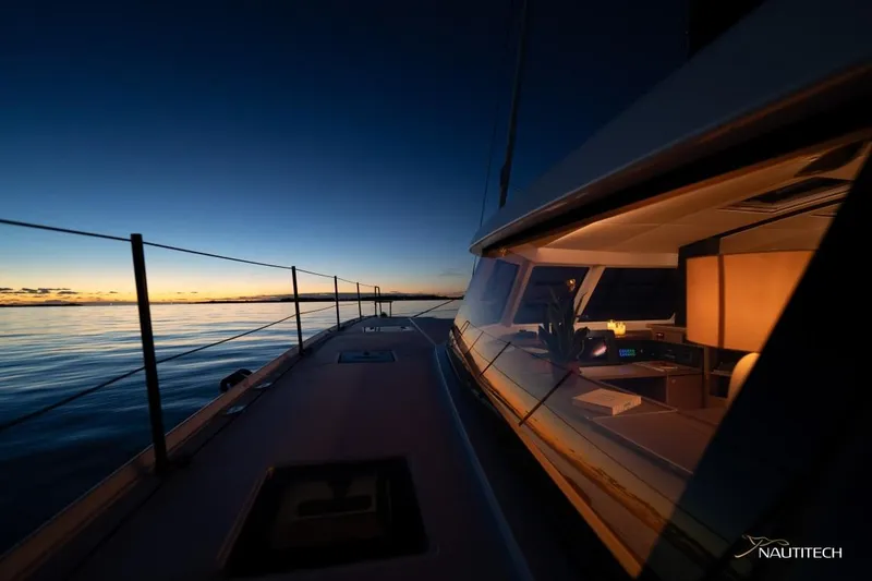 Slide: The Image of The Nautitech 48 Open sails at sunset. The cabin is warmly lit. - 25