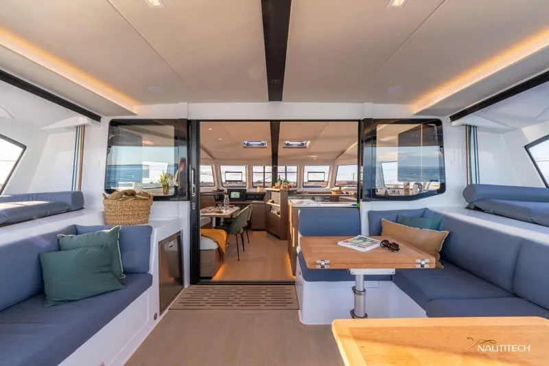 Slide: The Image of Interior of a modern yacht with stylish seating and a dining table, surrounded by large windows. - 16