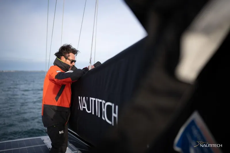 Slide: The Image of A man in a red jacket stands aboard a Nautitech 48 Open on the sea. - 22