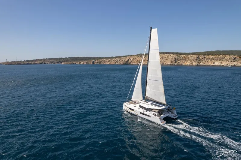 Slide: The Image of A Nautitech 44 Open catamaran sails on calm waters near a rocky coastline. - 4