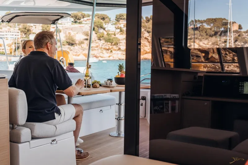 Slide: The Image of A couple sits in the dining area of a Nautitech 44 Open, overlooking the water. - 20