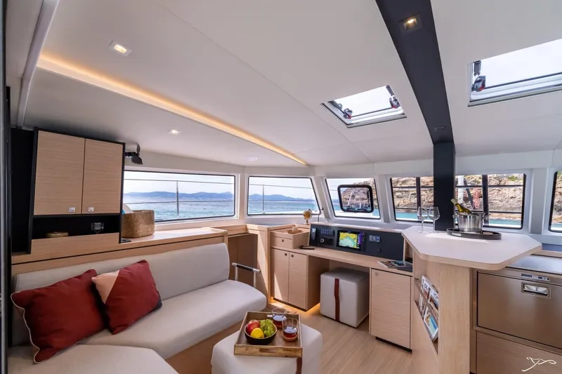 Slide: The Image of The interior of the 2027 Nautitech 44 Open features a modern design with large windows, a cozy sofa, and a well-equipped kitchen. - 40