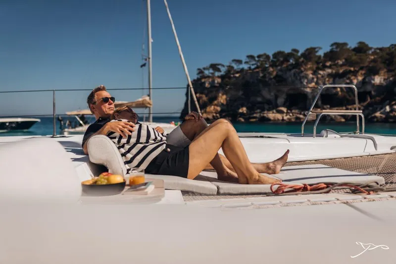 Slide: The Image of A man relaxes on a Nautitech 44 Open catamaran, surrounded by clear water and rocky cliffs. - 22