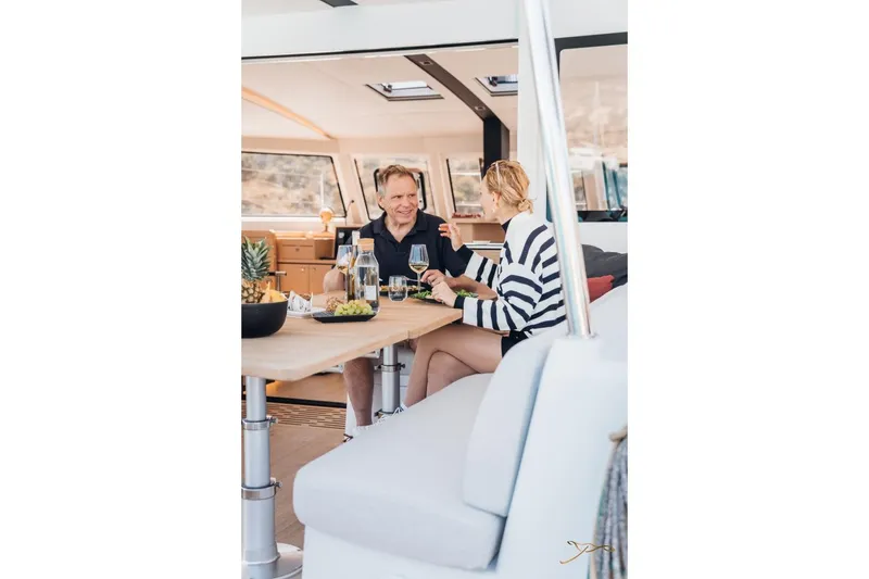 Slide: The Image of Two people sit at a table inside a modern yacht, enjoying drinks. - 19