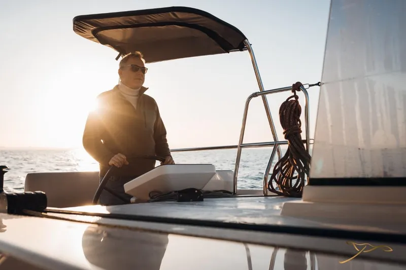 Slide: The Image of A person steering a Nautitech 44 Open at sunset. - 13