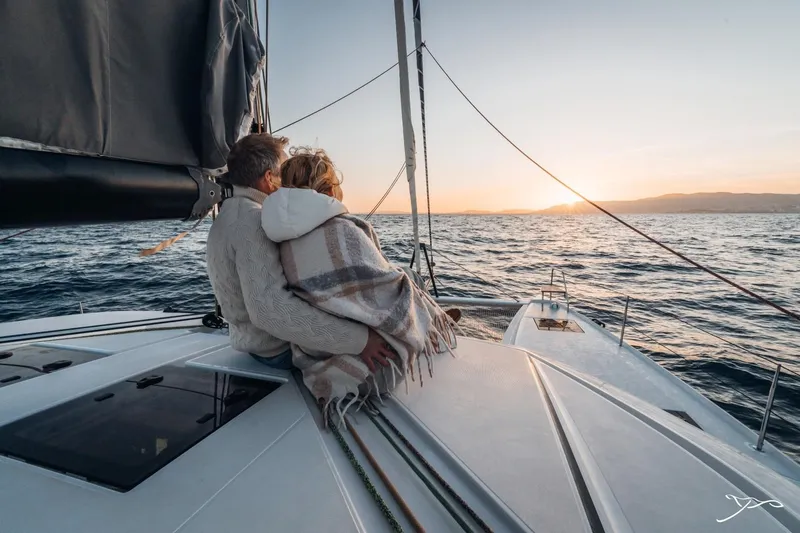 Slide: The Image of A couple sits on the deck of a Nautitech 44 Open, enjoying the sunset over the sea. - 27