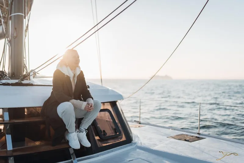 Slide: The Image of A person sits on a modern catamaran at sunset on the sea. - 14