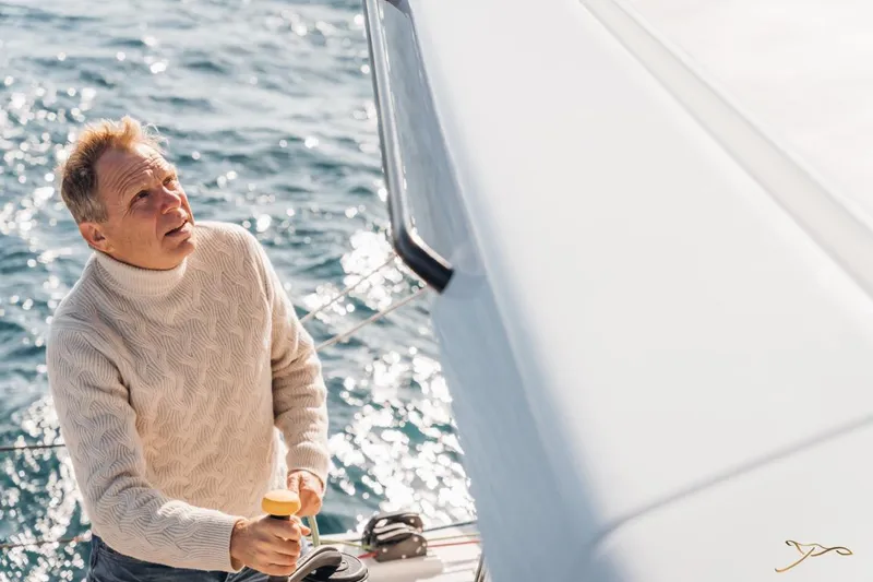 Slide: The Image of A man in a cream sweater stands on the deck of a boat at sea. - 17