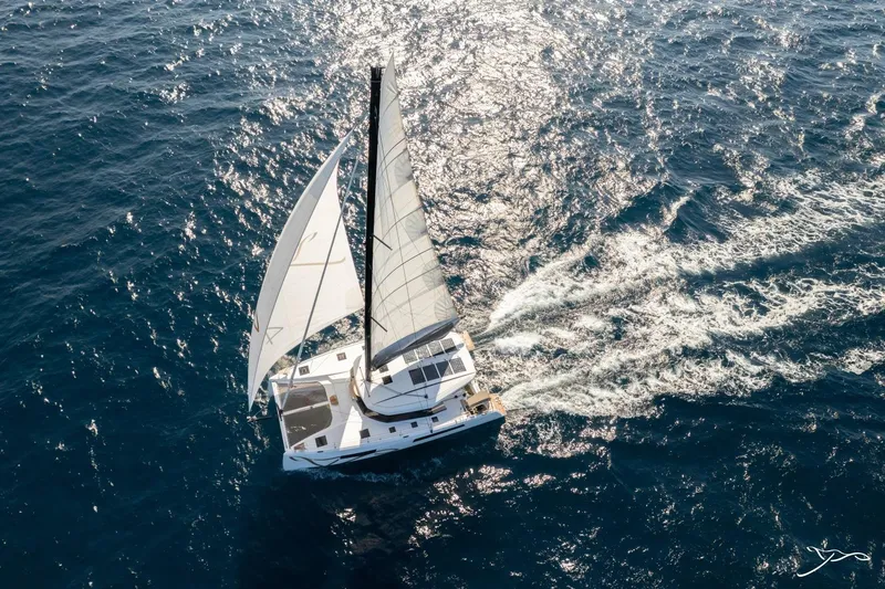 Slide: The Image of A modern sailing catamaran gliding over sparkling blue waters, featuring white sails and sleek design. - 2