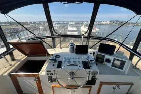Slide: The Image of 1978 Hatteras 58 Motor Yacht helm with marina view, featuring navigation instruments and steering wheel. - 30