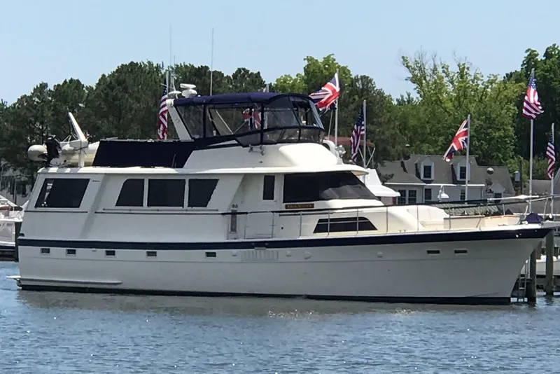 Slide: The Image of 1978 Hatteras 58 Motor Yacht docked, surrounded by flags and trees. - 4