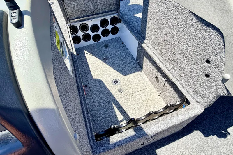 Slide: The Image of 2005 Alumacraft Tournament Sport 175 boat storage compartment with rod holders and carpeted interior. - 58
