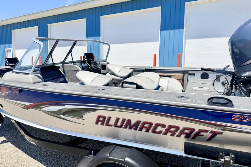 Slide: The Image of 2005 Alumacraft Tournament Sport 175 boat with sleek design, parked near blue building. - 7