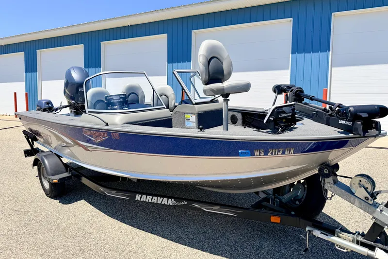 Slide: The Image of 2005 Alumacraft Tournament Sport 175 boat on trailer, parked near blue building. - 3