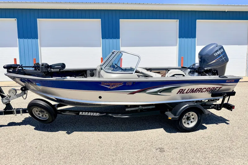 The Image of 2005 Alumacraft Tournament Sport 175 boat on trailer, parked near blue building. - 0