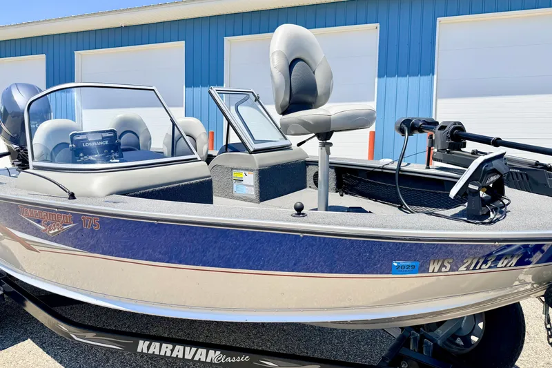Slide: The Image of 2005 Alumacraft Tournament Sport 175 boat with blue exterior, parked near a blue building. - 12