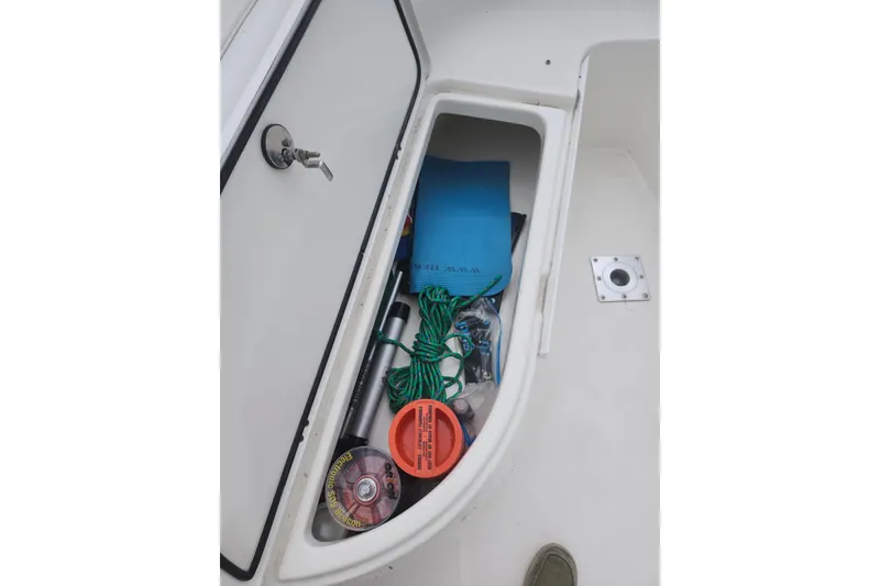 Slide: The Image of Storage compartment on a 2007 Edgewater 228CC boat, containing various boating accessories. - 22