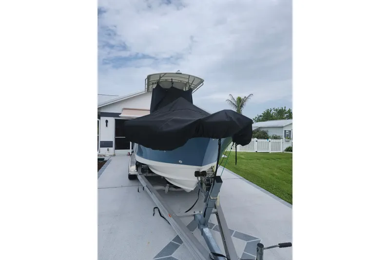 Slide: The Image of 2007 Edgewater 228CC boat on trailer with cover, parked in residential driveway. - 11