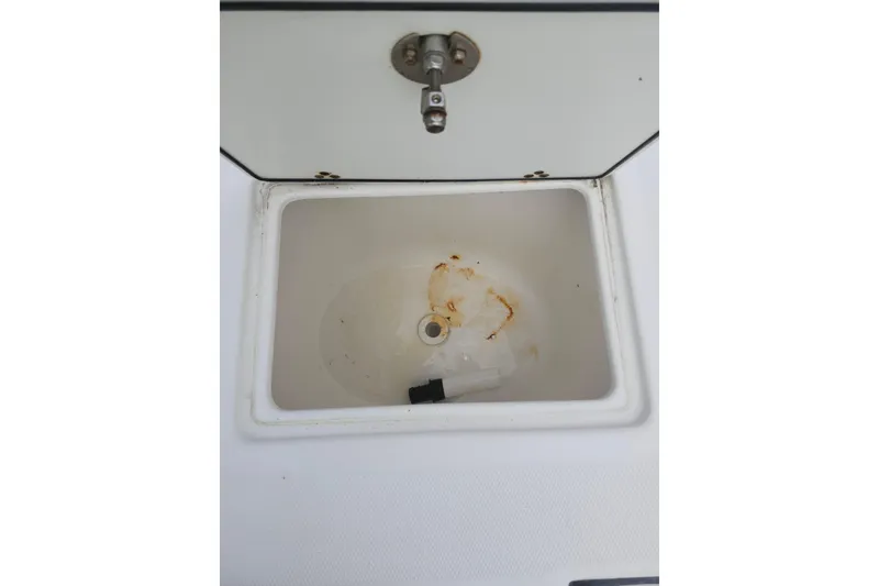 Slide: The Image of 2007 Edgewater 228CC boat compartment with drain, showing minor rust and wear. - 35