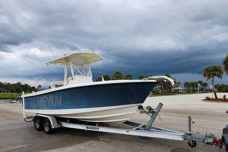 Slide: The Image of 2007 Edgewater 228CC boat on trailer, parked near palm trees under cloudy sky. - 9