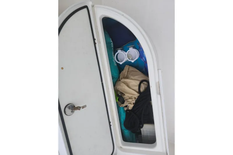 Slide: The Image of Storage compartment on a 2007 Edgewater 228CC boat with various items inside. - 23