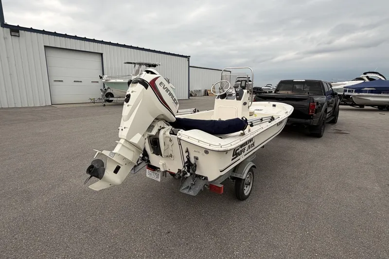 Slide: The Image of 2014 Carolina Skiff JV15CC boat on trailer, parked near a warehouse. - 8