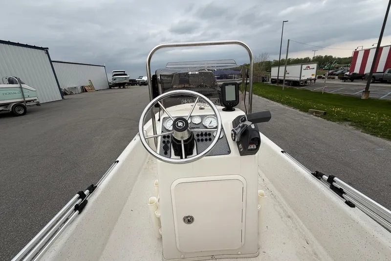 Slide: The Image of 2014 Carolina Skiff JV15CC boat console with steering wheel and controls, parked outdoors. - 14