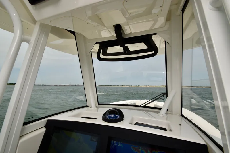 Slide: The Image of The image shows the cockpit of a 2023 Regulator 28 Forward Seating boat with a view of the water. - 34