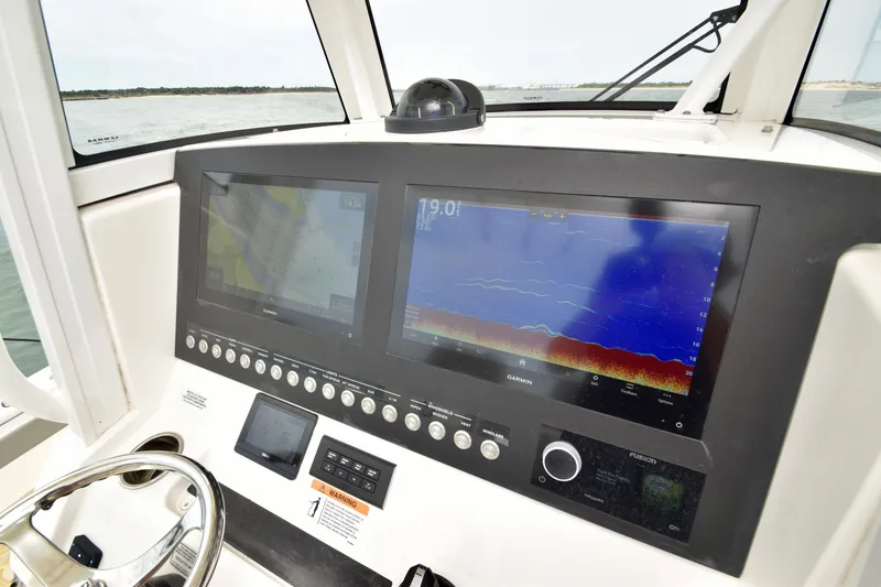 Slide: The Image of The image shows the dashboard of a Regulator 28 Forward Seating boat with modern navigation screens. - 32