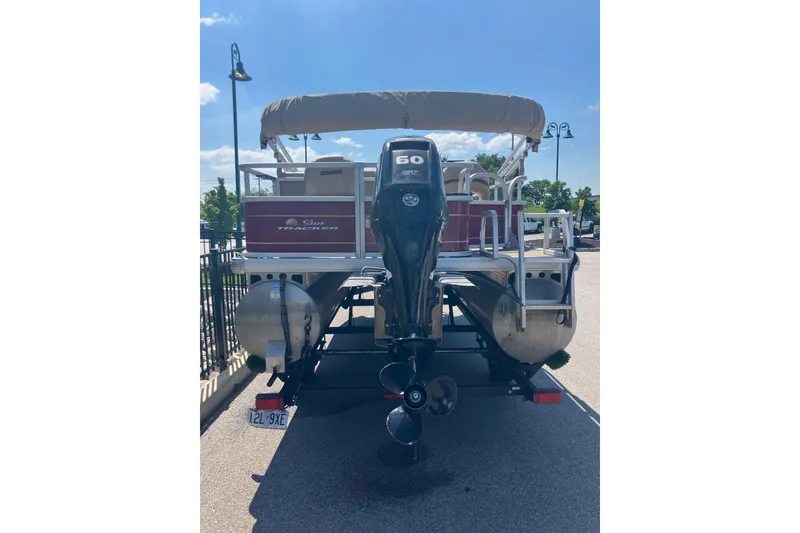 Slide: The Image of 2020 Sun Tracker Bass Buggy 18 DLX pontoon boat with outboard motor, parked outdoors. - 4