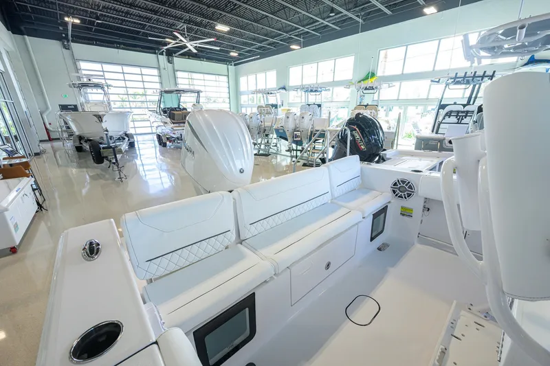 Slide: The Image of 2027 Sportsman Heritage 231 Center Console boat in showroom, featuring sleek white interior design. - 29