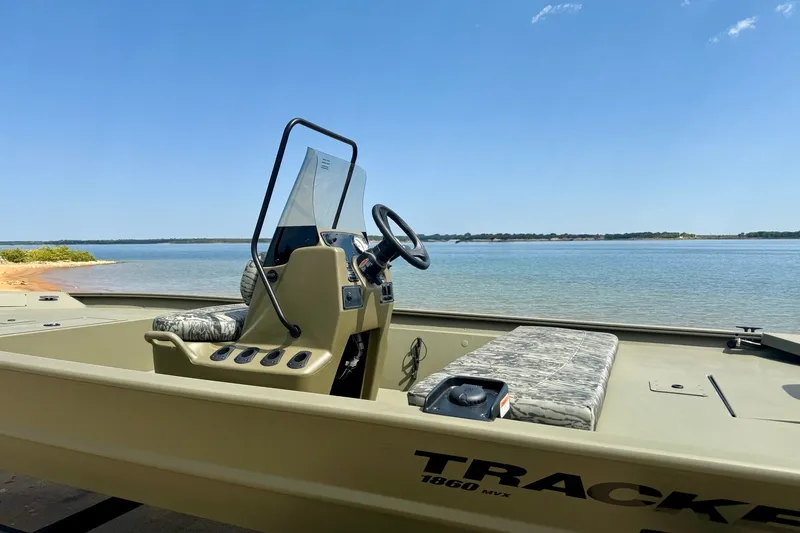 Slide: The Image of 2026 Tracker Grizzly 1860 CC boat on a serene lake under clear blue skies. - 14