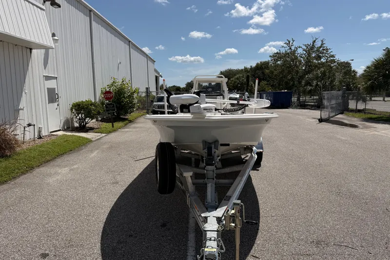 Slide: The Image of 2026 Mako 18 Pro Skiff boat on trailer, parked outdoors near industrial building. - 2