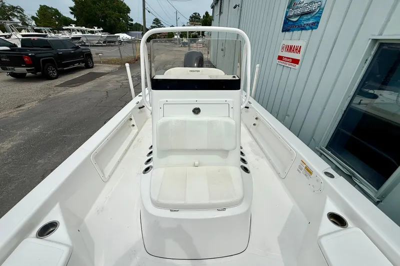 Slide: The Image of 2023 Frontier 2104 boat with white seating, docked near a marine shop. - 10