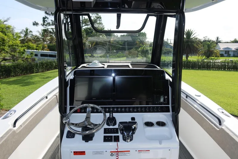 Slide: The Image of 2025 Sea Hunt Gamefish 28 Coffin Box boat console with dual screens and steering wheel. - 22