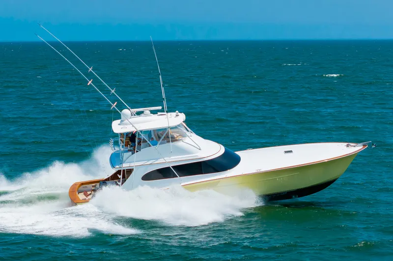 Slide: The Image of A 2022 Scarborough 63 speeds across the sea, featuring two long fishing rods on the roof. - 1