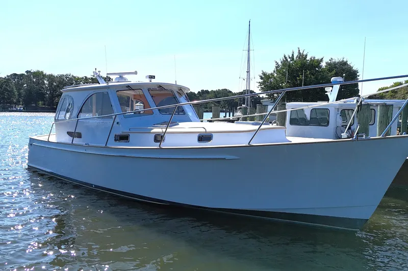 Slide: The Image of 2002 Legacy Express boat docked on calm water, surrounded by trees and clear sky. - 1