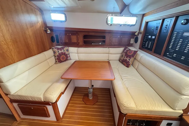 Slide: The Image of Cozy 2002 Legacy Express yacht interior with cushioned seating and wooden table. - 56