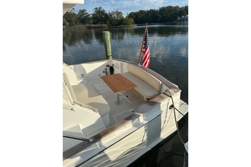 Slide: The Image of 2002 Legacy Express boat with seating area and American flag on calm water. - 43