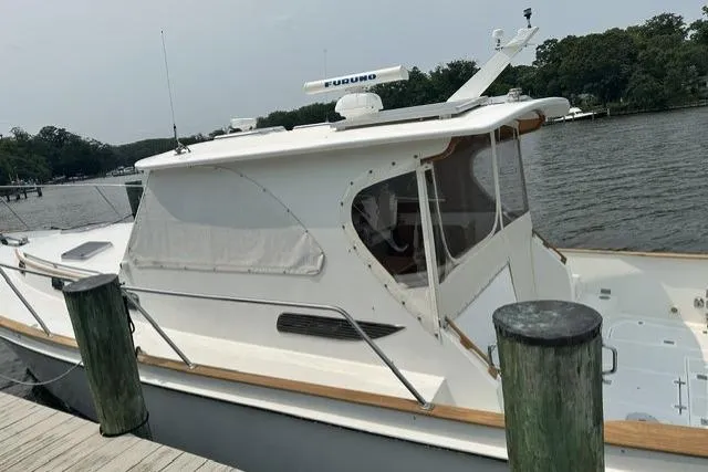 Slide: The Image of White 2002 Legacy Express boat docked by a serene lake with lush greenery. - 5