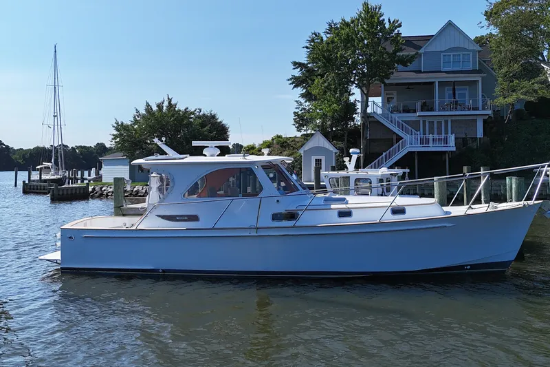 Slide: The Image of 2002 Legacy Express boat docked near waterfront house, clear blue sky. - 37
