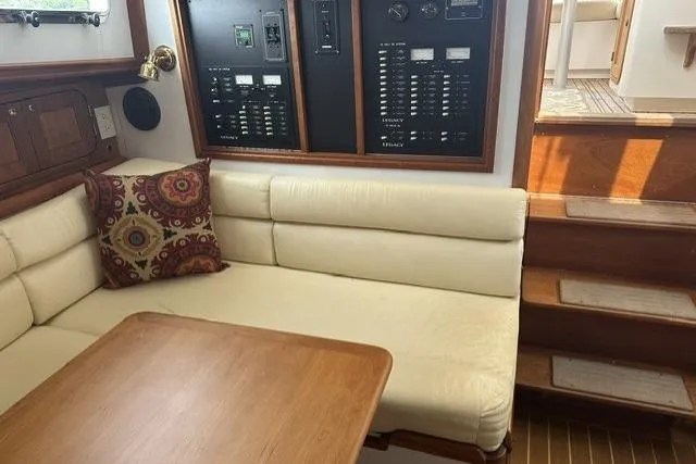 Slide: The Image of Cozy 2002 Legacy Express yacht interior with beige seating, wooden table, and control panels. - 16