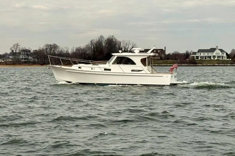 Slide: The Image of 2002 Legacy Express boat cruising on a calm waterway near shoreline homes. - 4