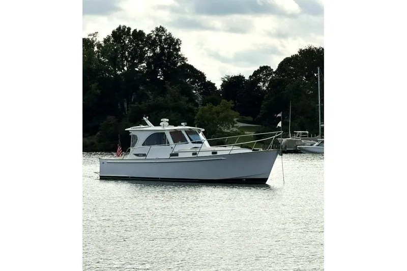 Slide: The Image of 2002 Legacy Express boat anchored on a calm lake with trees in the background. - 2