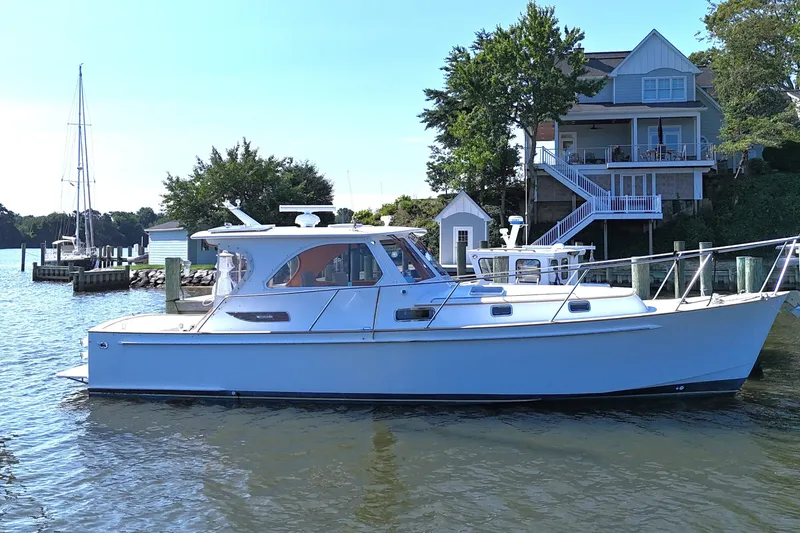 Slide: The Image of 2002 Legacy Express boat docked near waterfront house, surrounded by calm water and trees. - 3