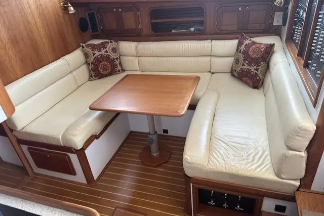 Slide: The Image of Cozy seating area in a 2002 Legacy Express boat with wooden table and cushions. - 17