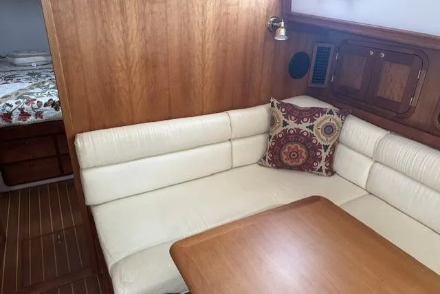 Slide: The Image of Cozy 2002 Legacy Express yacht interior with white seating, wooden accents, and decorative pillow. - 14